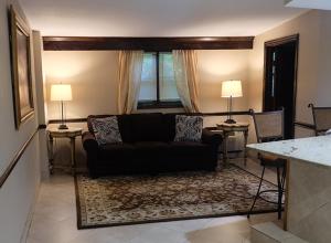Centerport恰勒特宾馆及套房的客厅配有黑色沙发和两盏灯。