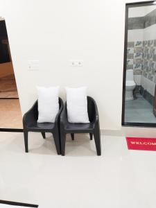 DoiwālaAirport Luxury Nature Valley Homestay的两把带白色枕头的黑色椅子,坐在镜子旁