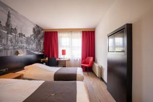格罗宁根巴斯琛哥罗普酒店的酒店客房,设有两张床和一张红色椅子