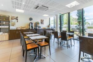 波城All Suites Pau – Zénith的用餐室设有桌椅和窗户。