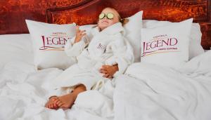 派尔努传奇酒店的躺在床上的女人,戴着毛巾和太阳镜