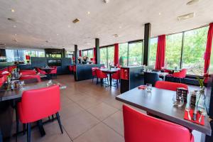 鹿特丹鹿特丹南巴斯蒂欧酒店的餐厅设有红色的椅子和桌子以及窗户。