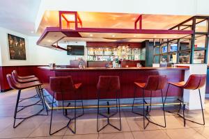 鹿特丹鹿特丹南巴斯蒂欧酒店的餐厅的酒吧,餐厅设有红色酒吧凳