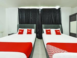 瓜拉丁加奴Super OYO 90364 Hotel Gemilang的客房内的两张床和红色枕头