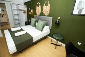 瓦伦西亚Total Valencia Torres de Quart的一间卧室配有一张带绿色墙壁的床和一把椅子