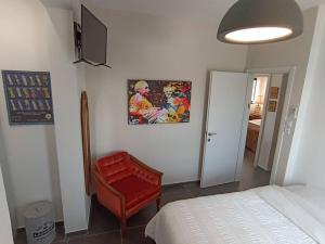 纳哈里亚Hoffman Executive Suites - Beachfront Nahariya的一间卧室配有一张床和一张红色椅子