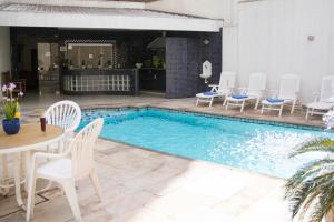 坎皮纳斯马里亚诺皇宫酒店的游泳池配有白色的椅子、桌子和桌椅