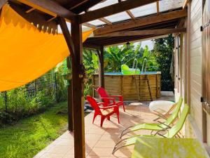勒拉芒坦Magnifique Lodge en bois avec piscine et jardin de 800 m2的一个带红色和绿色椅子的庭院和热水浴缸