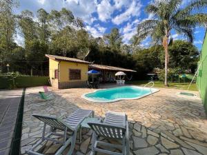 伊塔蒂亚亚Casa de Campo em Penedo - RJ的后院设有游泳池、椅子和房屋
