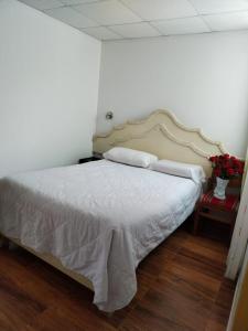 乌鲁班巴Hotel Quilla House 2的一间卧室配有白色床单和鲜花。