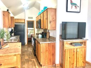 奥斯汀The Coyote Cabin - Cabins at Rim Rock的一间带木制橱柜和平面电视的厨房
