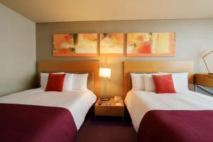 墨西哥城卡米诺里尔圣塔菲酒店的酒店客房带两张带红白色枕头的床