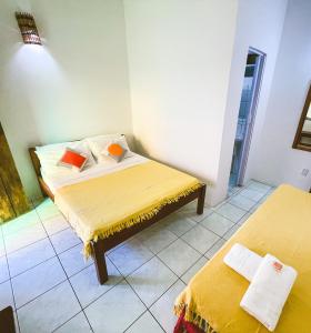 伊塔卡雷Buddy's Hostel Itacaré的一间卧室配有两张带黄色床单和橙色枕头的床。
