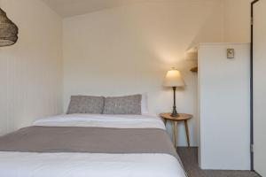 托菲诺麦肯齐海滩度假酒店的一间卧室配有一张床和一张桌子上的台灯