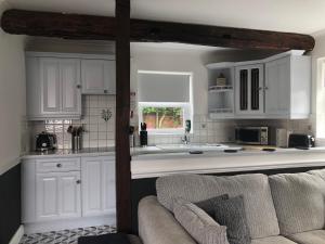 DenbyTHE GARDEN SUITE的厨房配有白色橱柜和沙发。