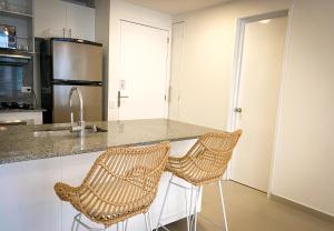 卡塔赫纳Apartamento en Cartagena con vista al mar的厨房在柜台上配有两把藤椅