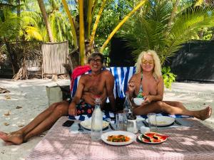马米基里White Tern Maldives的两人坐在海滩上的野餐桌上