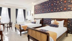 梭罗MAHALAYA The Legacy Hotel的酒店客房设有两张床和一张桌子。