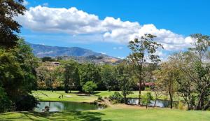 Ciudad CariariLOP Inn San Jose Aeropuerto - Costa Rica的一座带池塘和山脉的高尔夫球场