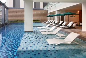 宿务Holiday Inn Cebu City, an IHG Hotel的一个带白色躺椅的游泳池,铺有蓝色瓷砖地板