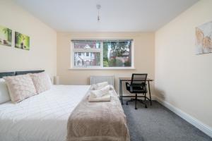 红山Redhill Surrey 2 Bedroom Pet Friendly Apartment by Sublime Stays的一间卧室配有一张床、一张书桌和一个窗户。