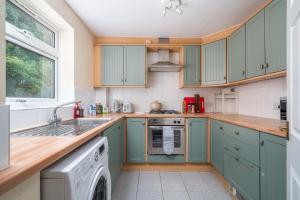 红山Redhill Surrey 2 Bedroom Pet Friendly Apartment by Sublime Stays的厨房配有蓝色橱柜和洗碗机。
