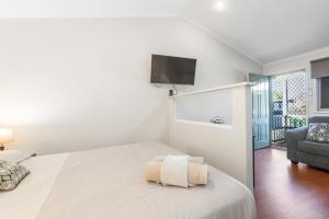 卡拉萨Aspen Karratha Village的白色卧室设有一张床和墙上的电视
