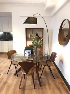 维希Vichy : Le 5e - Appartement design dans un ancien palace的一间设有玻璃桌和椅子的用餐室