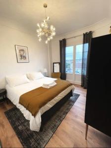 维希Vichy : Le 5e - Appartement design dans un ancien palace的一间卧室配有一张大床和一个吊灯。