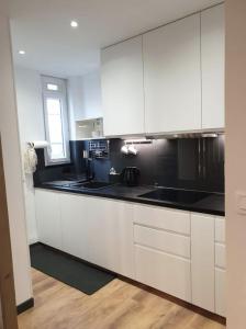 维希Vichy : Le 5e - Appartement design dans un ancien palace的厨房配有白色橱柜和黑色台面