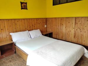 大吉岭Hotel Mhelung的卧室配有白色床和黄色墙