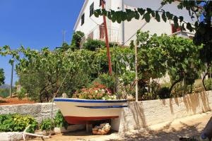 萨利Apartments by the sea Sali, Dugi otok - 8110的坐在房子旁的花园中的船