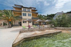 布里尼Apartments by the sea Savar, Dugi otok - 8128的一座带椅子和遮阳伞的房子和一个游泳池