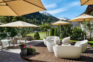 图克斯拉讷斯巴赫布鲁格美食酒店的庭院配有白色的桌椅和遮阳伞。