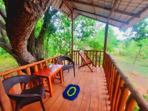 达瓦拉维La Casa Safari Resort的木甲板上配有桌椅和一棵树