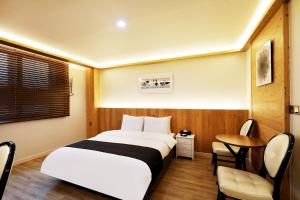 扶安Buan Tourist Hotel的酒店客房带一张床、一张桌子和椅子