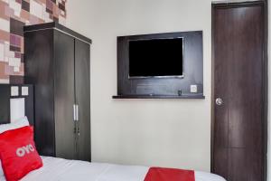 加拉旺OYO 91646 fio colombus residence的一间卧室配有一张床和一台平面电视