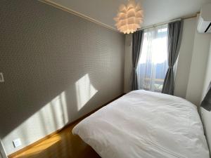 名古屋Villa Monica的卧室配有白色的床和窗户。