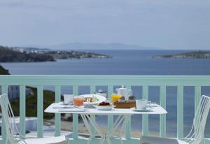 米克诺斯城Bill & Coo Mykonos -The Leading Hotels of the World的阳台上配有带食品和饮料的白色桌子
