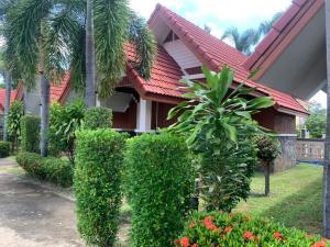 甘烹碧Bunraksa Resort的前面有灌木和鲜花的房子