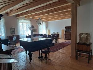 陶尔曹尔Tarcal Apartman的一间设有钢琴的房间和一间带椅子的用餐室