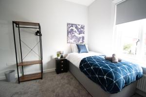 RoytonIdeal Lodgings in Royton的一间卧室配有一张带蓝色毯子的床和窗户。