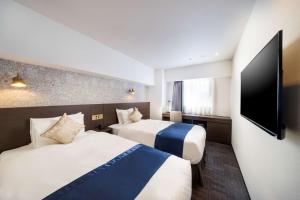 横滨Best Western Hotel Fino Shin-Yokohama的酒店客房设有两张床和一台平面电视。