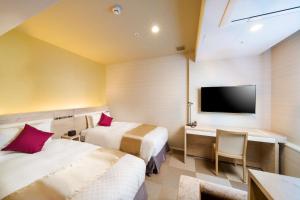 东京Best Western Hotel Fino Tokyo Akasaka的酒店客房设有两张床、一张桌子和一台电视。