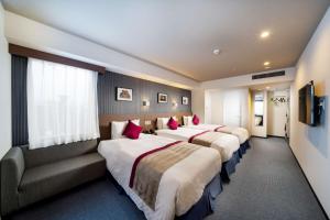 福冈Best Western Plus Fukuoka Tenjin-minami的酒店客房,设有三张床和一张沙发