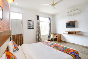 古尔冈FabHotel Aravali Suites的一间卧室配有一张床、一张书桌和一台电视。