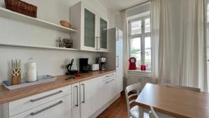 奥斯赛拜-塞林Villa Sonneck – Wohnung 15的厨房配有白色橱柜和木桌
