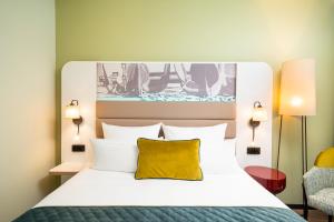 汉堡Leonardo Hotel Hamburg Altona的一间卧室配有一张带黄色枕头的大床