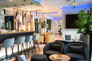 汉堡Leonardo Hotel Hamburg Altona的餐厅内的酒吧配有椅子和柜台
