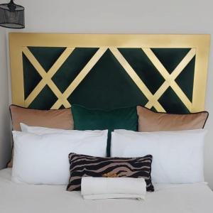 比勒陀利亚Elegant Airbnb的一张带白色枕头的床和绿色和金色床头板